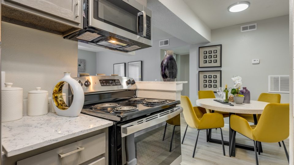 kitchen with white cabinets, stainless steel appliances and yellow chairs at The  Tatum